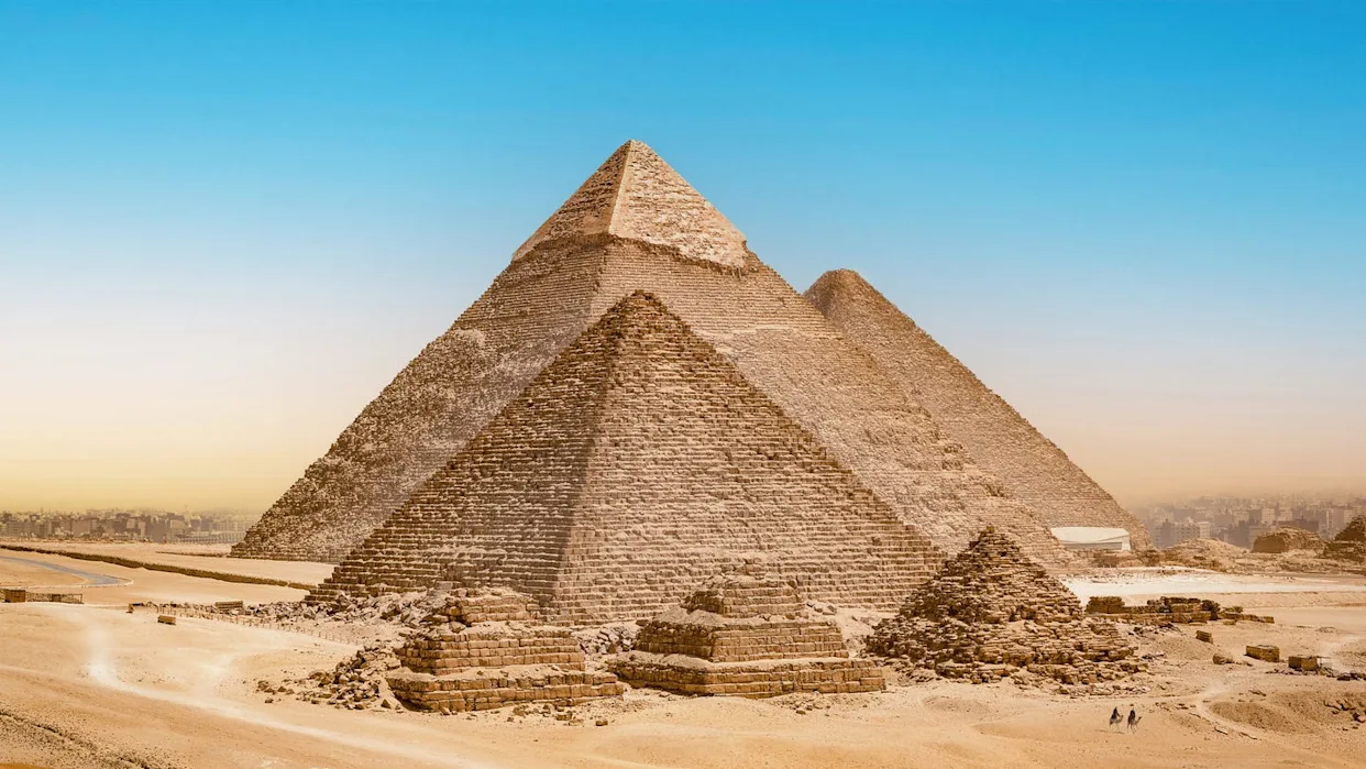 Aerial view of desert ruins beside a large pyramid; a red outlined rectangle marks an area of interest with a multicolored survey overlay.