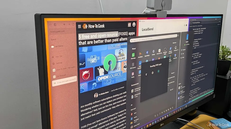 1000049127 Wide computer monitor on a desk showing multiple overlapping windows, including a How-To Geek article on the left and a dark application panel on the right.